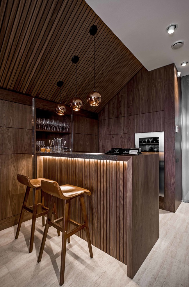 Zweizeilige Moderne Hausbar mit Bartheke, dunklen Holzschränken, Arbeitsplatte aus Holz, beigem Boden und flächenbündigen Schrankfronten in Sonstige