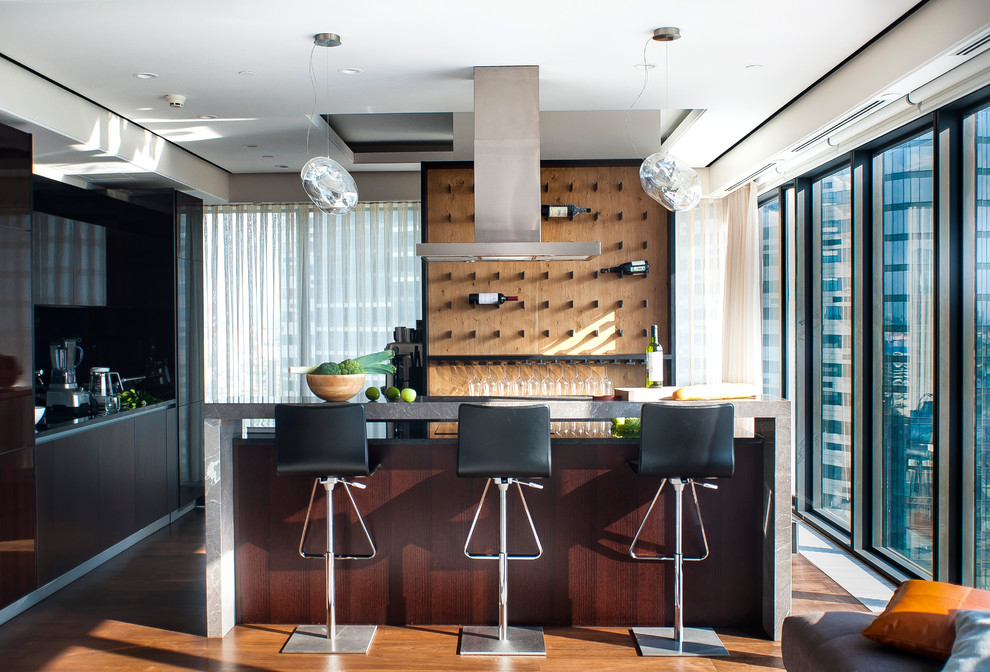 Photo of a contemporary l-shaped breakfast bar in Moscow with flat-panel cabinets, dark wood cabinets, brown splashback, wood splashback, medium hardwood flooring, brown floors and grey worktops.