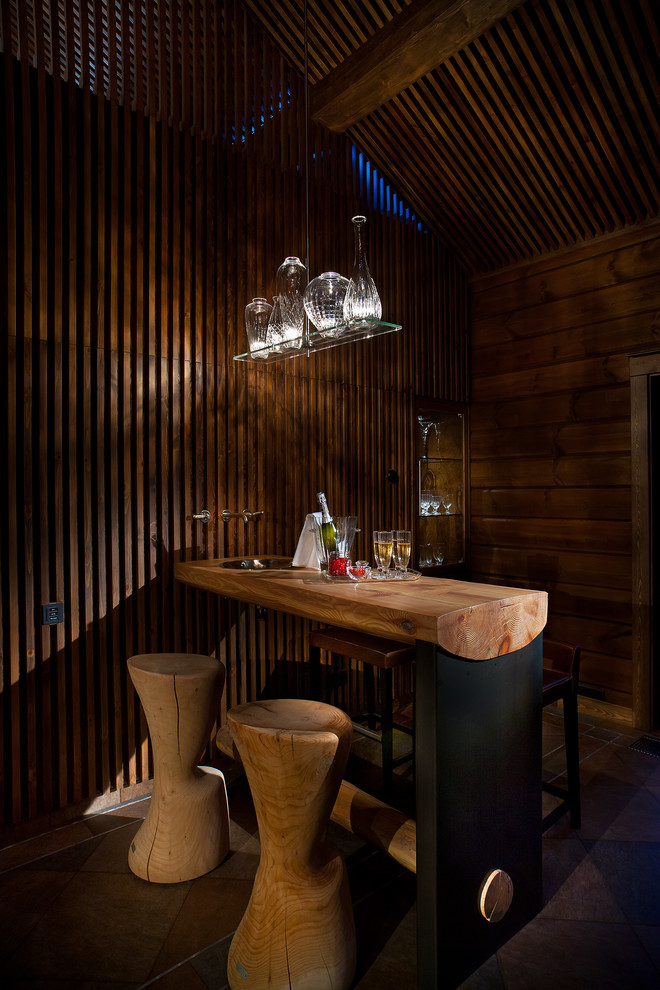 Aménagement d'un bar de salon montagne avec des tabourets, un plan de travail en bois et un plan de travail marron.