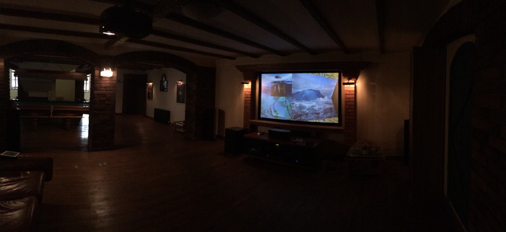 Ejemplo de cine en casa abierto tradicional de tamaño medio con paredes amarillas, suelo de madera pintada, pantalla de proyección y suelo marrón