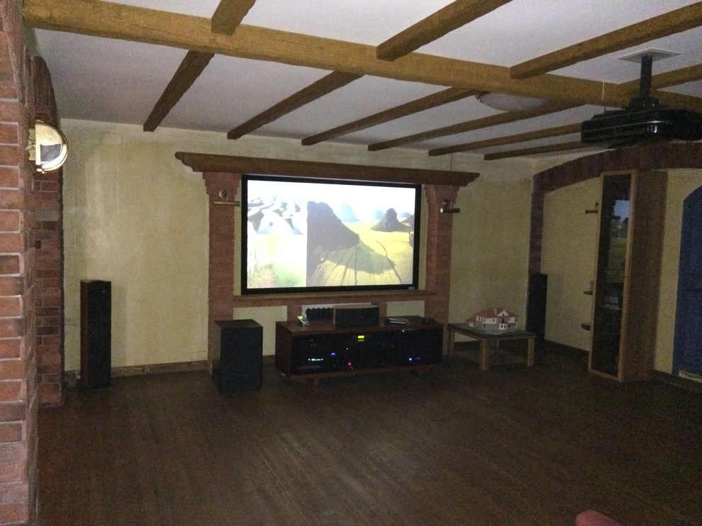 Modelo de cine en casa abierto tradicional de tamaño medio con paredes amarillas, suelo de madera pintada, pantalla de proyección y suelo marrón