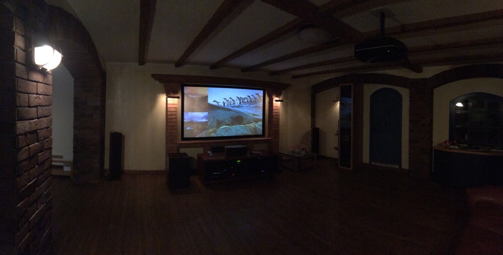 Ejemplo de cine en casa abierto clásico de tamaño medio con paredes amarillas, suelo de madera pintada, pantalla de proyección y suelo marrón