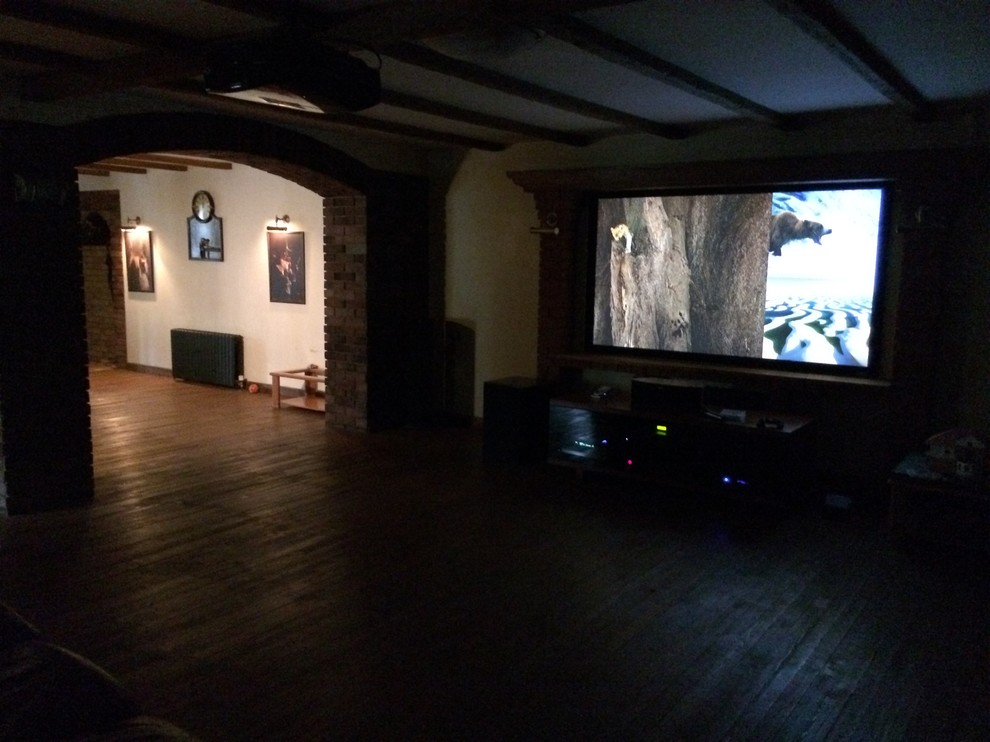 Imagen de cine en casa abierto tradicional de tamaño medio con paredes amarillas, suelo de madera pintada, pantalla de proyección y suelo marrón