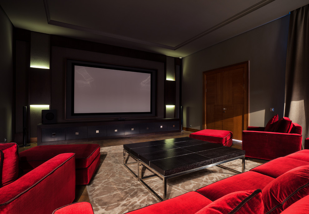 Modelo de cine en casa cerrado contemporáneo con suelo de madera en tonos medios, pantalla de proyección y suelo marrón