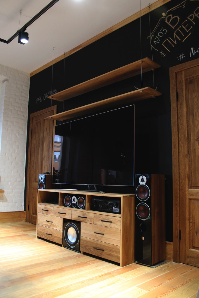 This is an example of a medium sized scandinavian home cinema in Saint Petersburg with black walls, light hardwood flooring and a built-in media unit.