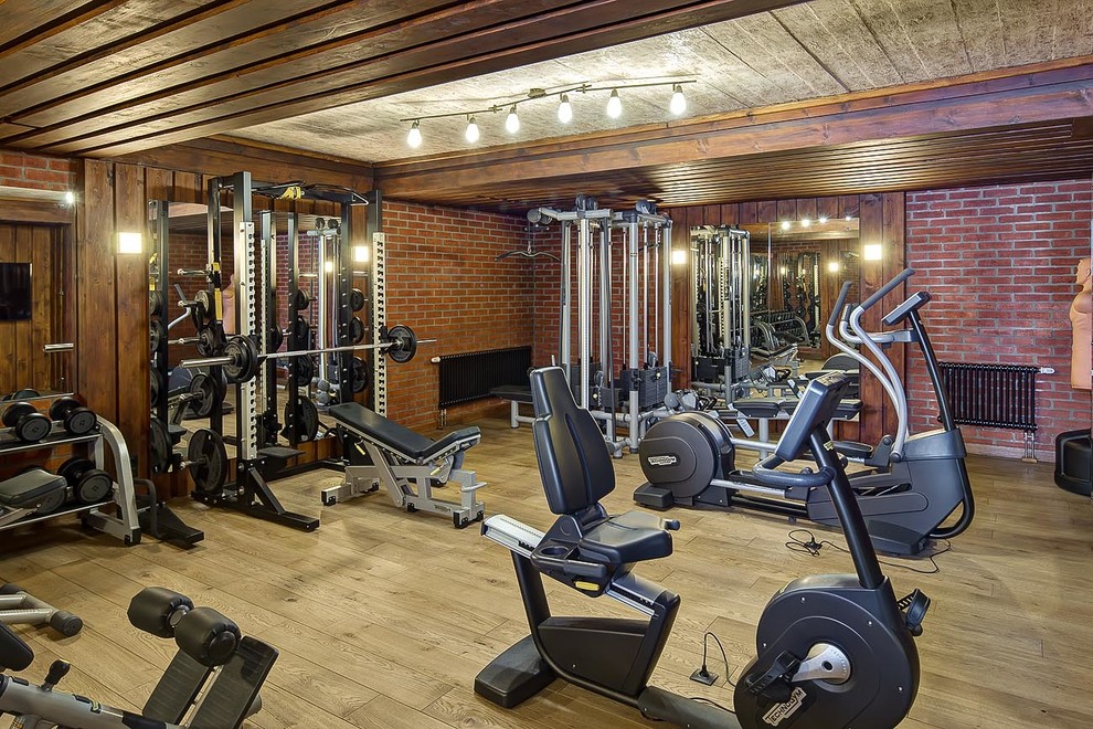Immagine di una sala pesi country con pareti marroni, pavimento in legno massello medio e pavimento marrone