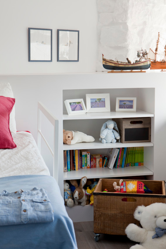 This is an example of a medium sized mediterranean gender neutral children’s room in Barcelona with white walls.