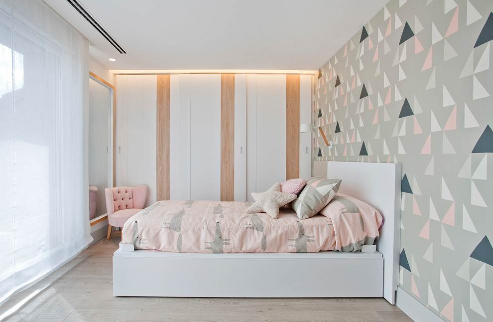 Small contemporary children’s room for girls in Other with white walls, light hardwood flooring and brown floors.