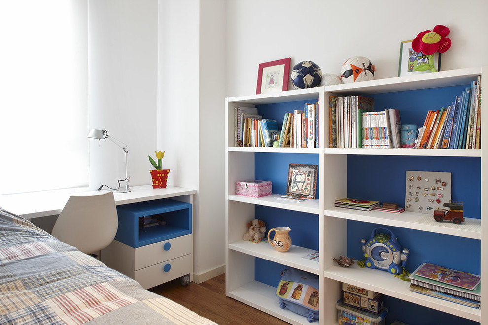 Inredning av ett minimalistiskt mellanstort pojkrum kombinerat med sovrum och för 4-10-åringar, med vita väggar och mellanmörkt trägolv