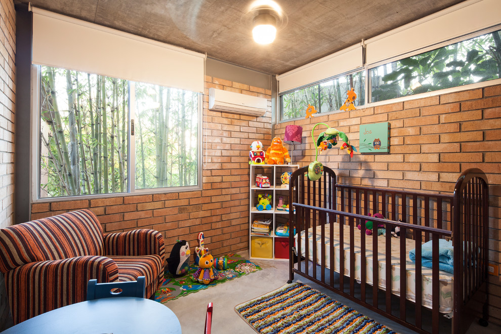 Modelo de dormitorio infantil de 1 a 3 años contemporáneo de tamaño medio con paredes beige y suelo de cemento