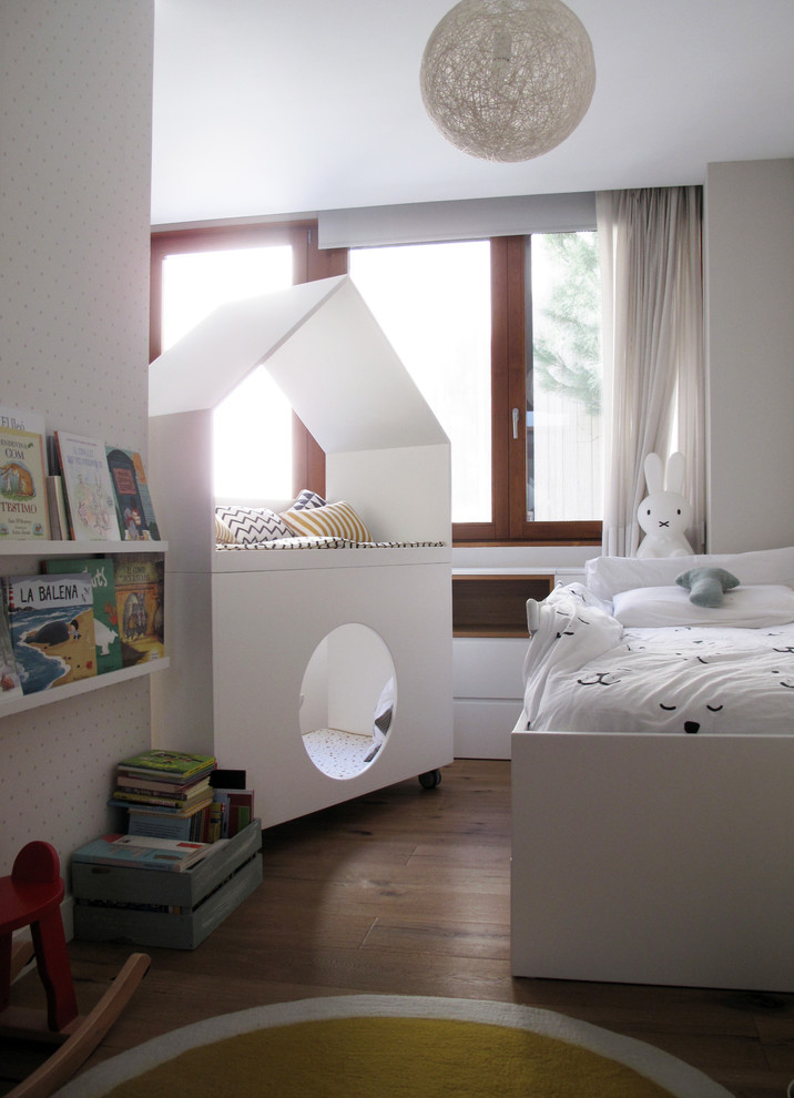 Esempio di una cameretta per bambini da 1 a 3 anni design di medie dimensioni con pareti bianche, pavimento in legno massello medio e pavimento marrone