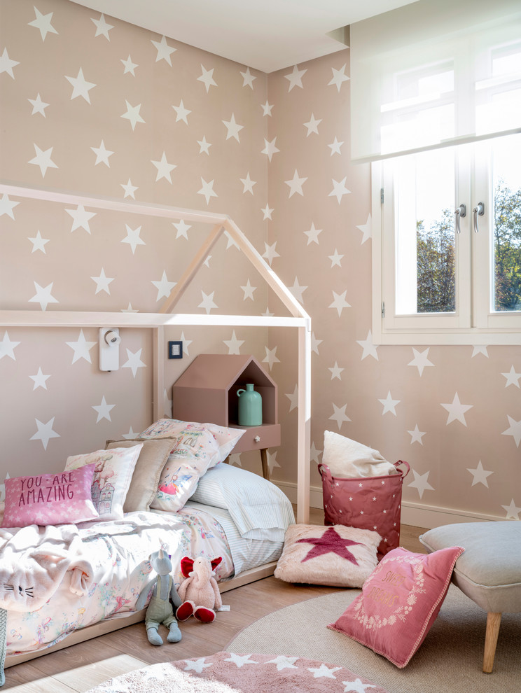 Cette image montre une grande chambre d'enfant de 1 à 3 ans nordique avec un mur rose, sol en stratifié et un sol marron.