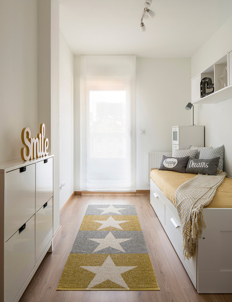 Imagen de dormitorio infantil nórdico con paredes blancas, suelo de madera en tonos medios y suelo marrón
