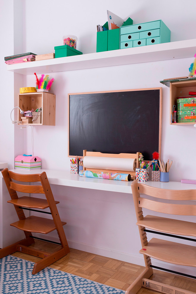 Imagen de habitación de niña de 4 a 10 años actual pequeña con paredes blancas, suelo de madera en tonos medios y escritorio