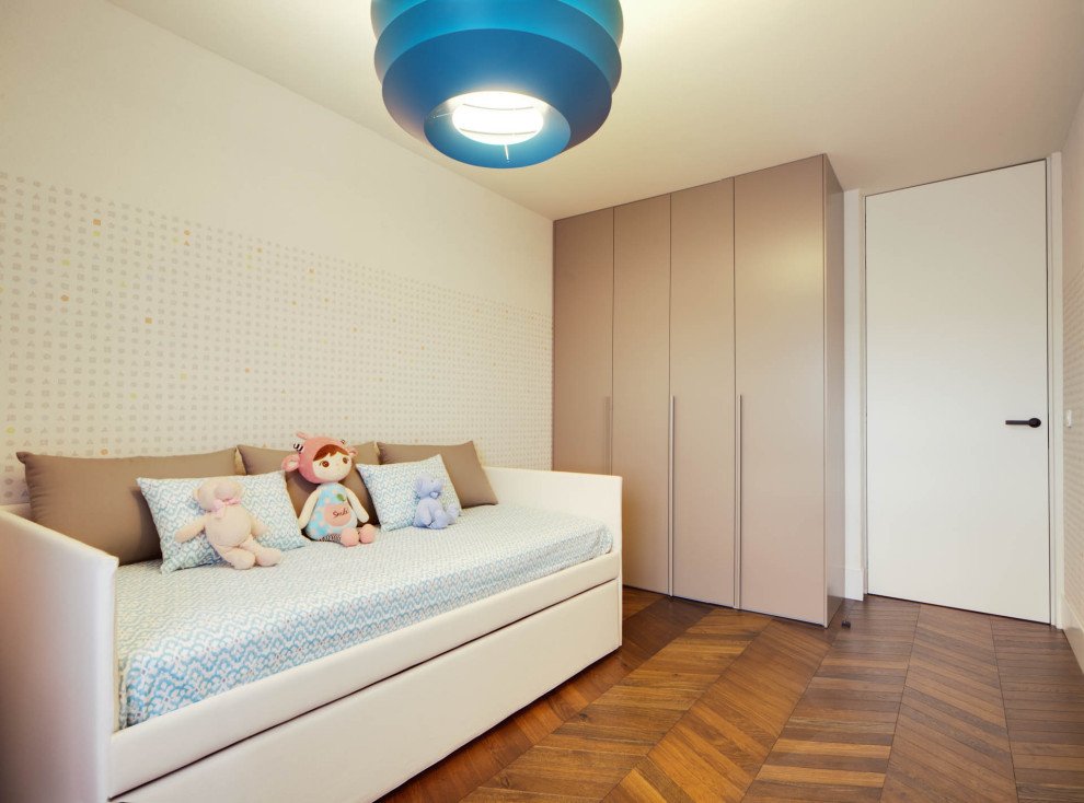 Cette photo montre une grande chambre d'enfant de 1 à 3 ans tendance avec un mur blanc, un sol en bois brun et un sol marron.