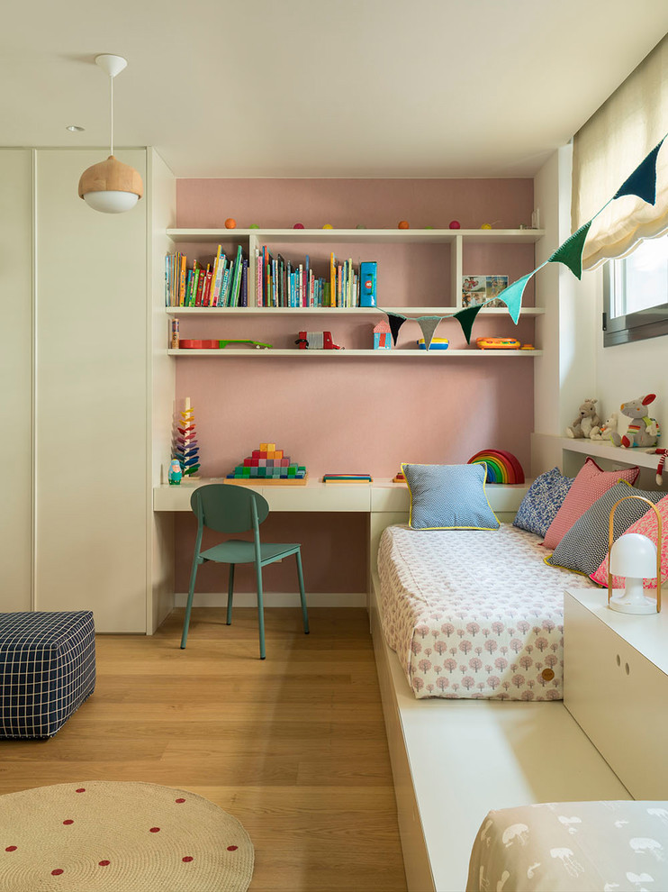 Idée de décoration pour une grande chambre d'enfant de 4 à 10 ans design avec un mur rose, un sol en bois brun et un sol marron.