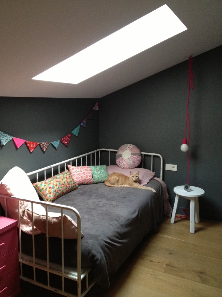 Foto på ett litet skandinaviskt könsneutralt barnrum kombinerat med sovrum och för 4-10-åringar, med svarta väggar och mellanmörkt trägolv
