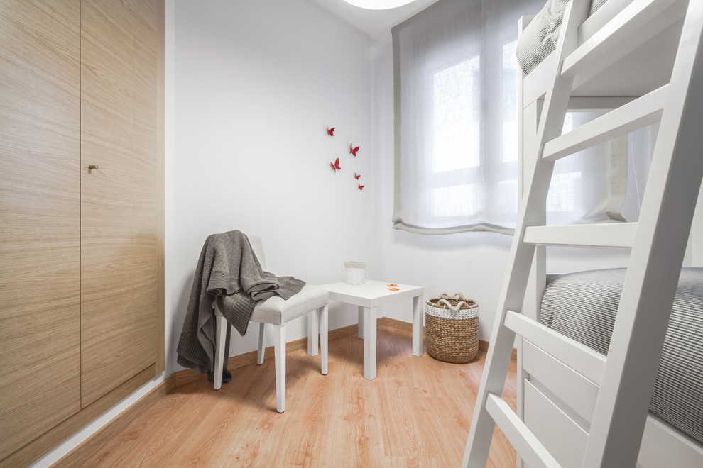 Ejemplo de dormitorio infantil de 4 a 10 años escandinavo de tamaño medio con paredes blancas y suelo de madera clara