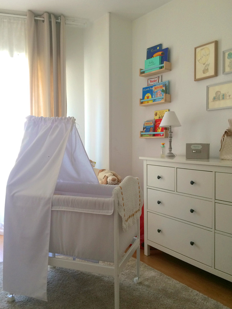 Klassisk inredning av ett litet könsneutralt småbarnsrum kombinerat med sovrum, med vita väggar, mellanmörkt trägolv och beiget golv