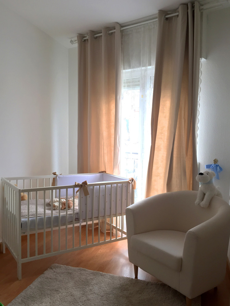 Esempio di una piccola cameretta per neonati neutra classica con pareti bianche, pavimento in legno massello medio e pavimento beige