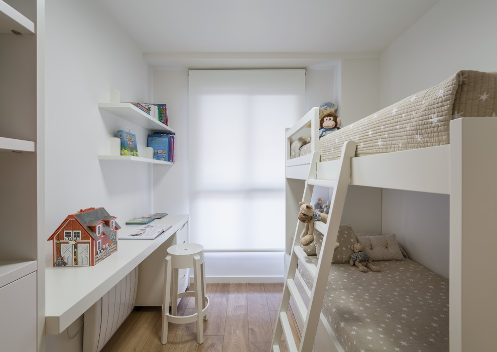This is an example of a medium sized scandinavian gender neutral children’s room in Madrid with white walls and medium hardwood flooring.