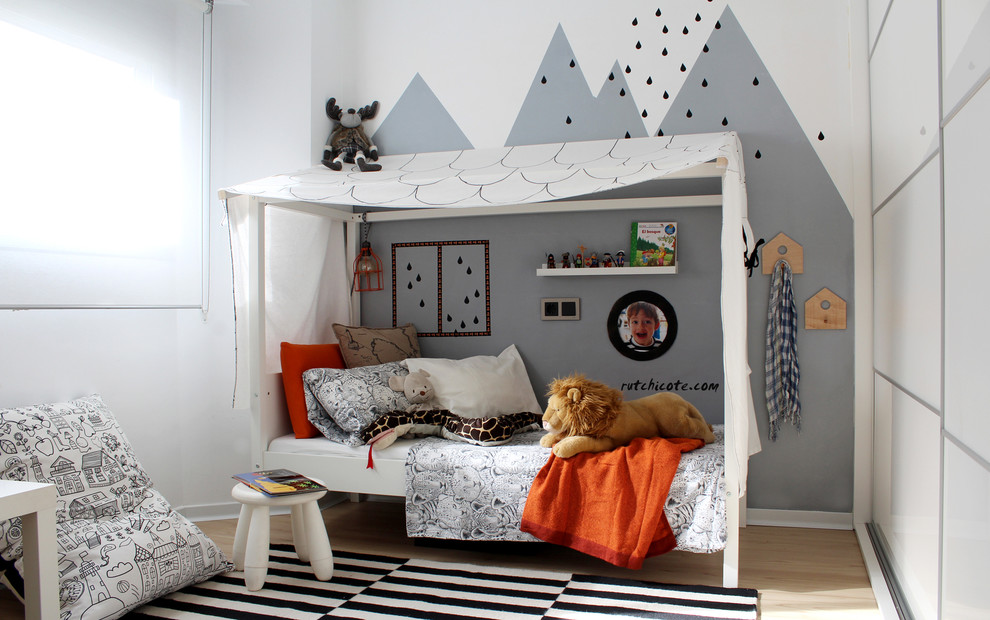 Inredning av ett klassiskt mellanstort pojkrum kombinerat med sovrum och för 4-10-åringar, med flerfärgade väggar och ljust trägolv