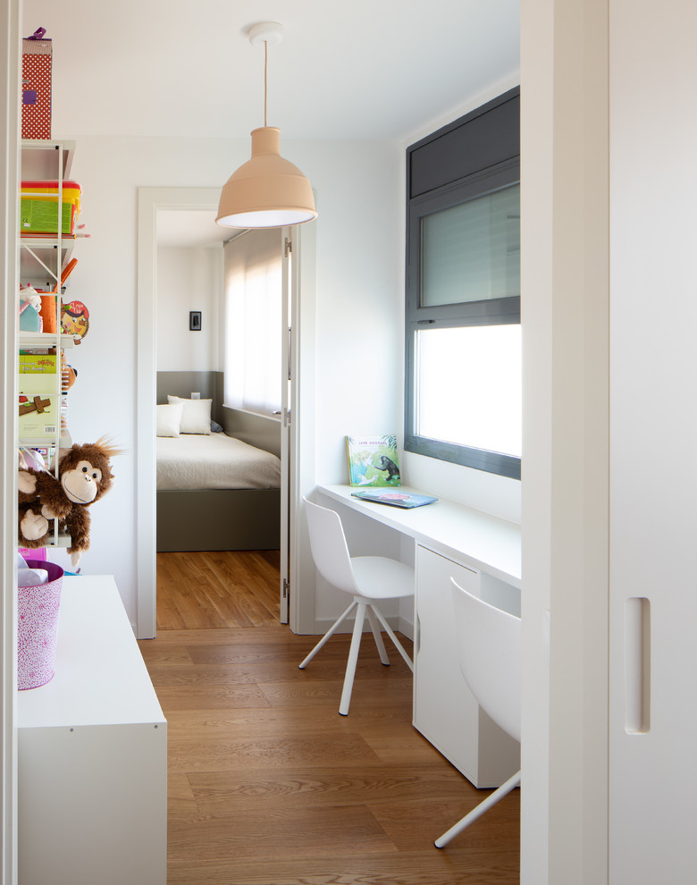 Diseño de habitación infantil unisex contemporánea con escritorio, paredes blancas, suelo de madera en tonos medios y suelo marrón