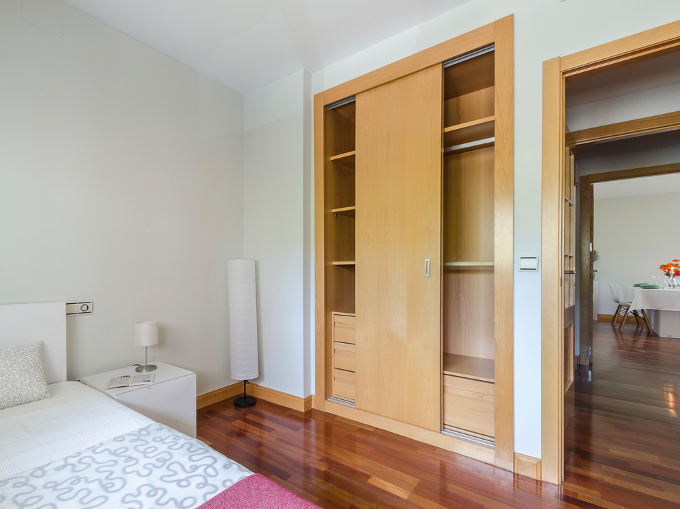 Modelo de dormitorio infantil contemporáneo de tamaño medio con paredes blancas, suelo de madera en tonos medios y suelo marrón