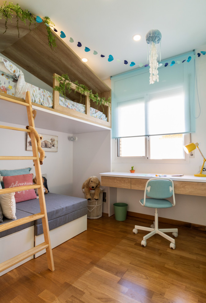 Imagen de habitación infantil unisex de 4 a 10 años nórdica de tamaño medio con escritorio, paredes blancas, suelo de madera en tonos medios y suelo marrón