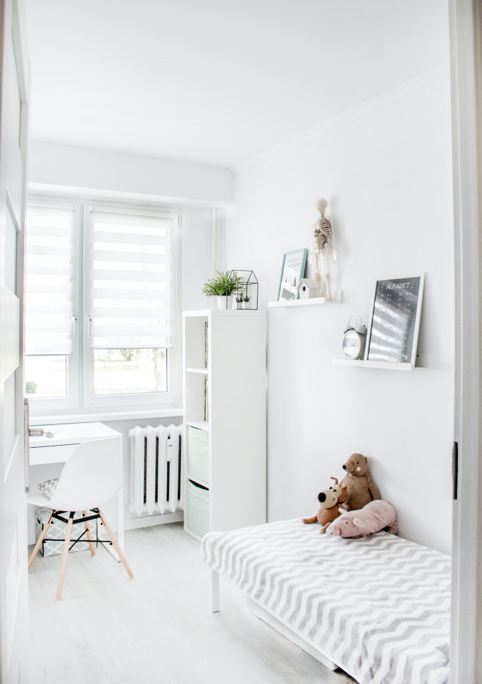 Immagine di una cameretta per bambini nordica con pareti bianche, parquet chiaro e pavimento grigio