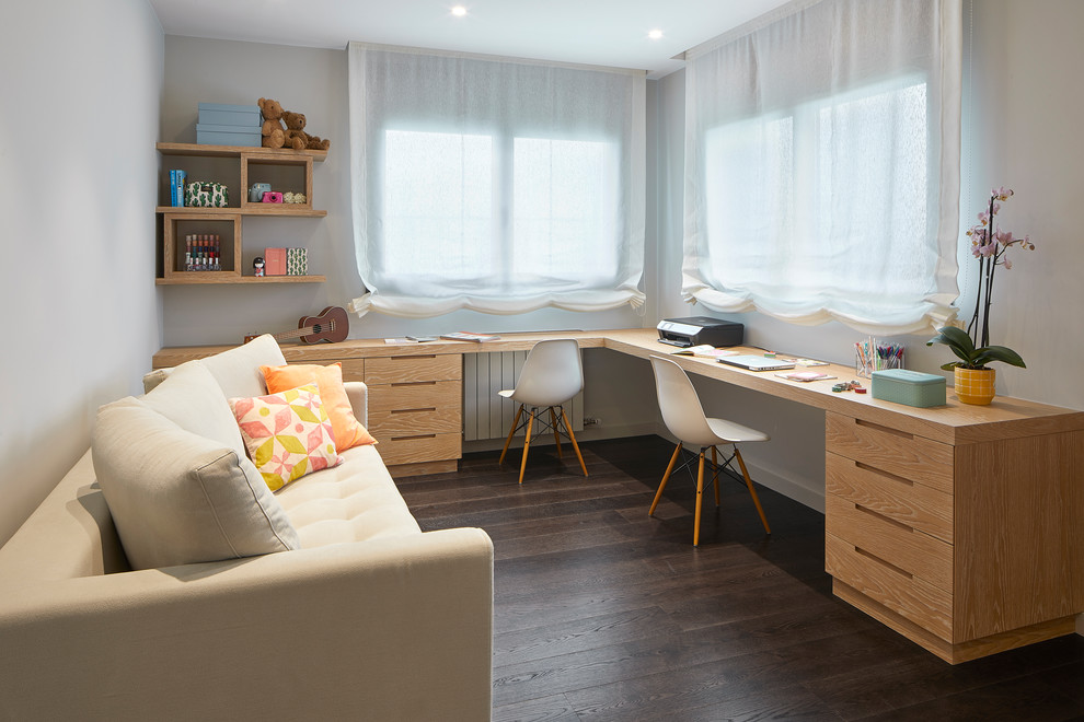 Inspiration för moderna könsneutrala barnrum kombinerat med skrivbord, med vita väggar, mörkt trägolv och brunt golv