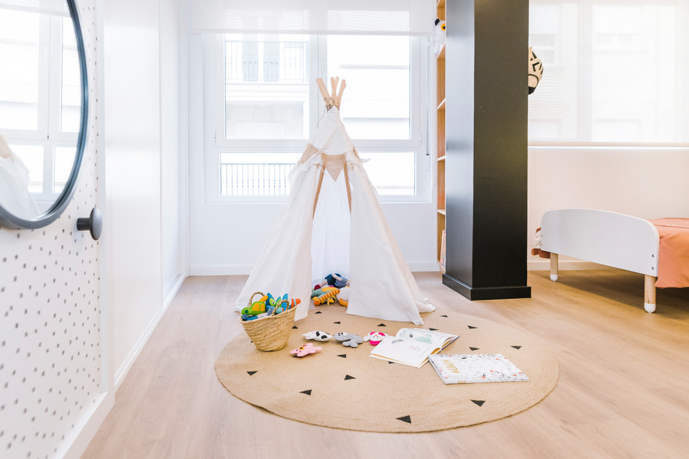 Cette photo montre une chambre d'enfant de 1 à 3 ans scandinave de taille moyenne avec un mur blanc, un sol en bois brun et un sol marron.