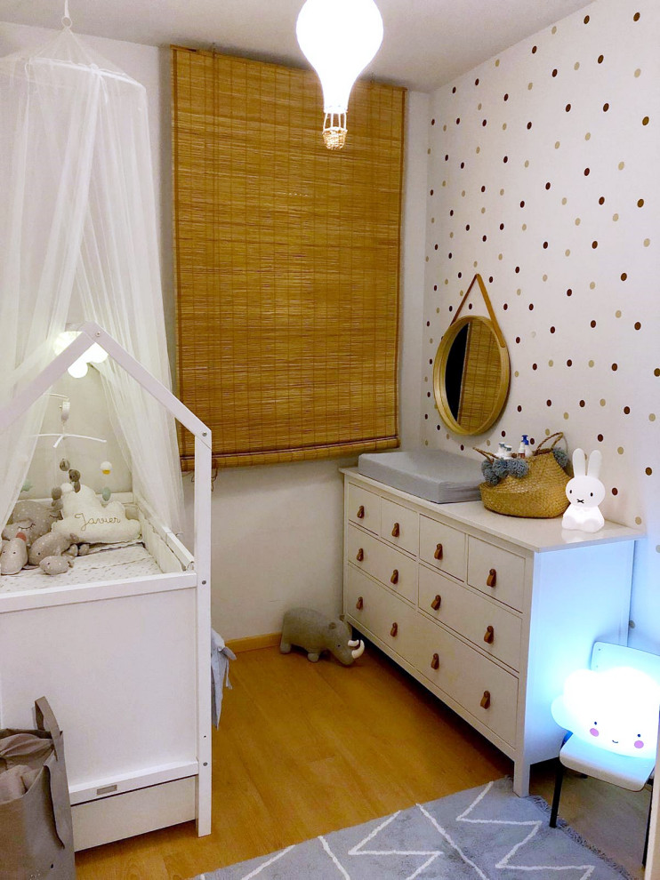 This is an example of a small scandinavian toddler’s room for boys in Madrid with white walls, laminate floors and brown floors.