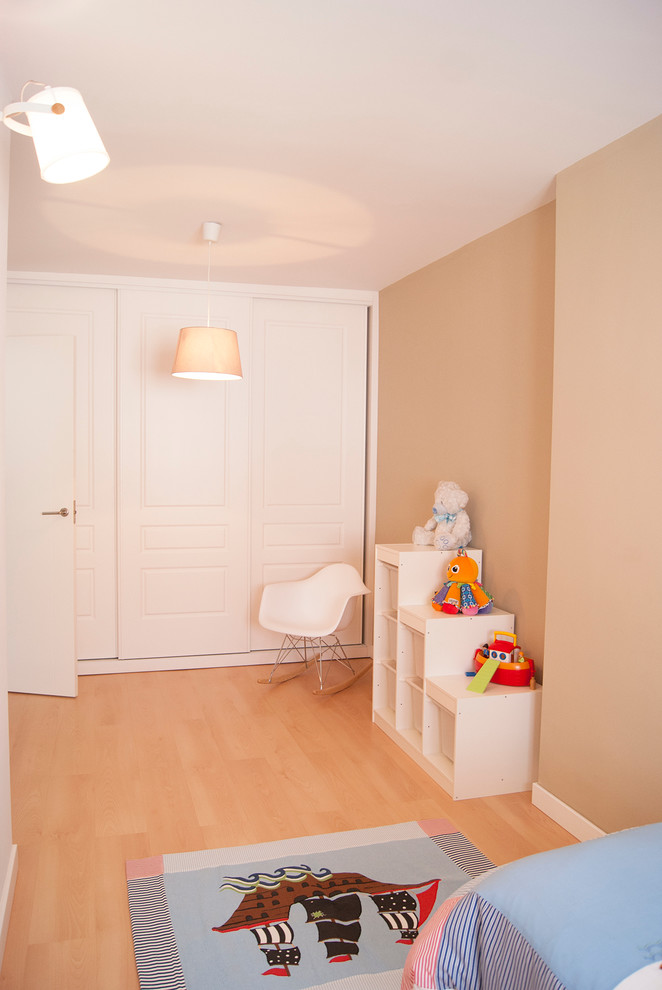 Modelo de dormitorio infantil de 4 a 10 años actual de tamaño medio con paredes beige y suelo de madera en tonos medios