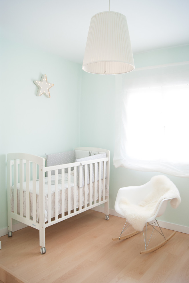 Foto de habitación de bebé neutra actual de tamaño medio con paredes azules y suelo de madera en tonos medios