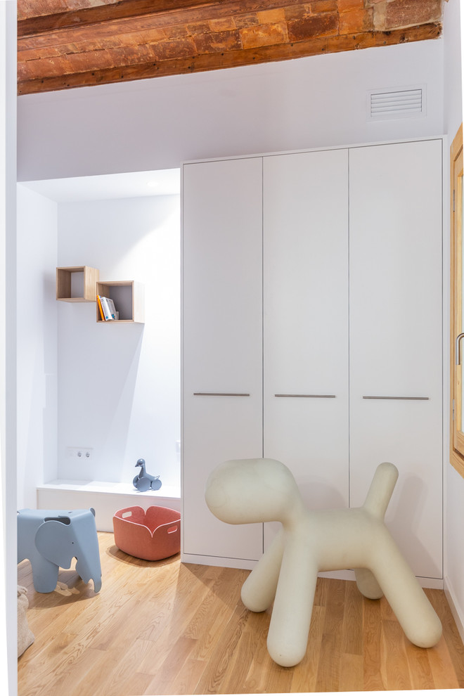 Immagine di una piccola cameretta per bambini da 4 a 10 anni mediterranea con pareti bianche, parquet chiaro e pavimento marrone