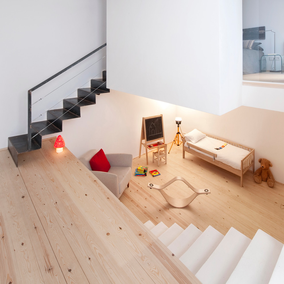 Medium sized scandinavian gender neutral toddler’s room in Barcelona with white walls and light hardwood flooring.