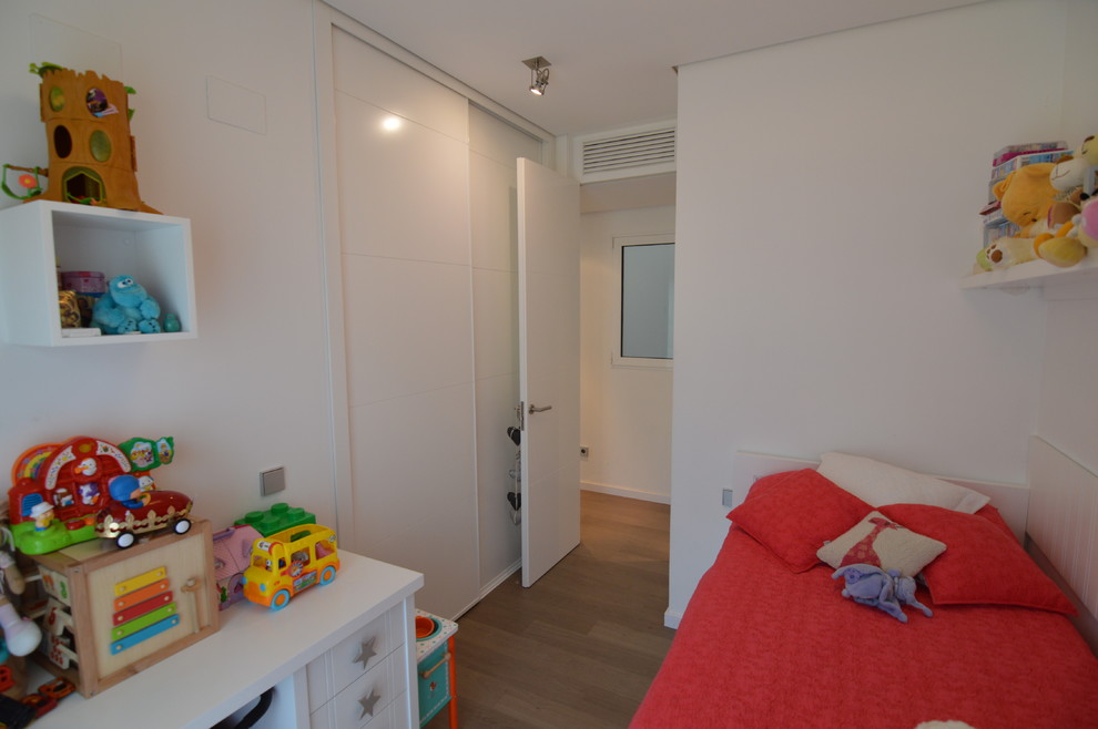 Ejemplo de dormitorio infantil de 4 a 10 años tradicional renovado pequeño con paredes blancas y suelo de madera en tonos medios