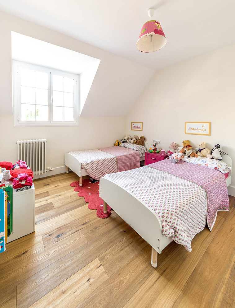 Immagine di una cameretta per bambini da 4 a 10 anni scandinava di medie dimensioni con pareti bianche e pavimento in legno massello medio