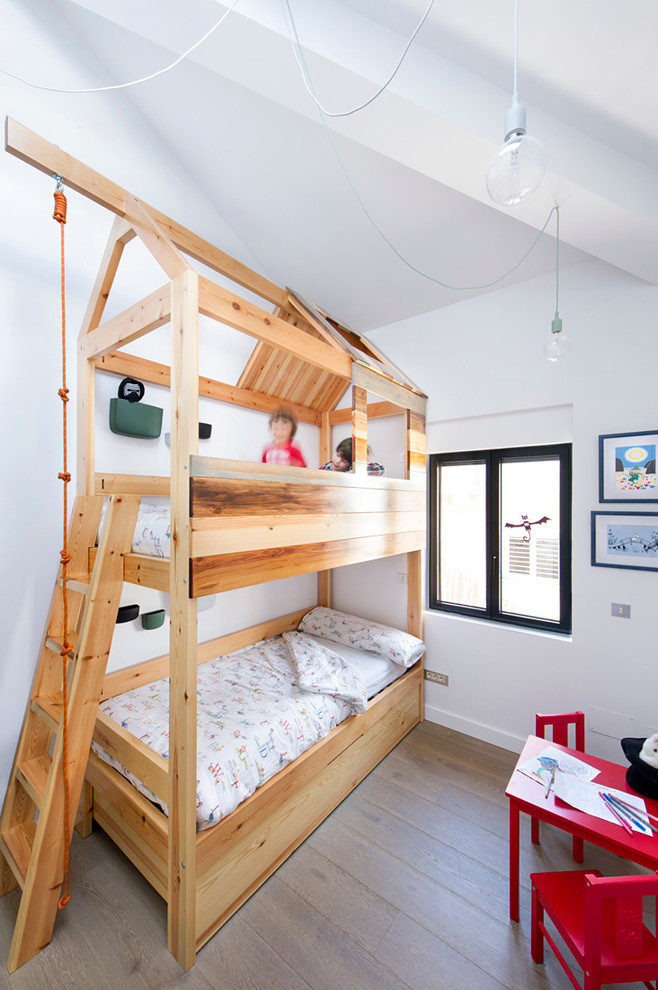 Idéer för ett mellanstort modernt könsneutralt småbarnsrum kombinerat med sovrum, med vita väggar och mellanmörkt trägolv