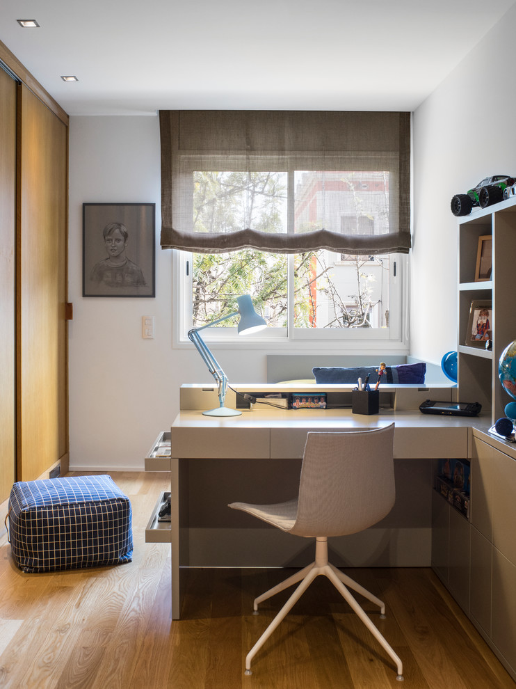 Cette image montre une chambre de garçon de 4 à 10 ans design de taille moyenne avec un mur blanc, un sol en bois brun, un bureau et un sol marron.