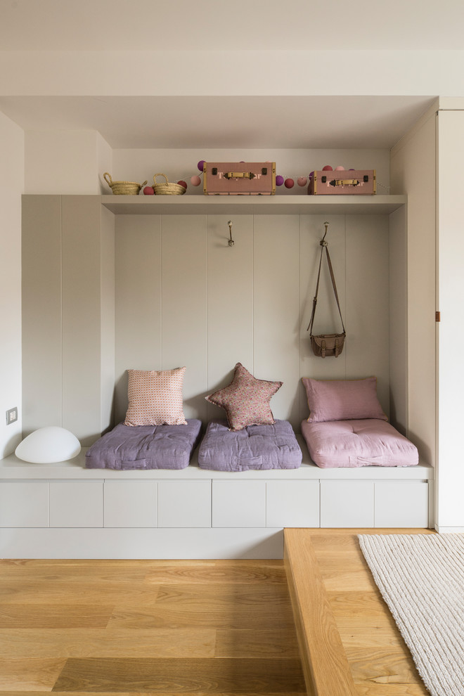 Inredning av ett modernt mellanstort flickrum kombinerat med sovrum och för 4-10-åringar, med vita väggar och mellanmörkt trägolv