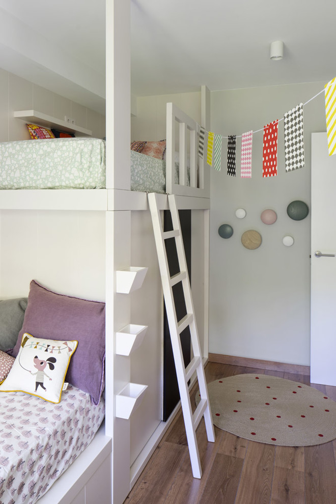 Esempio di una cameretta per bambini da 4 a 10 anni contemporanea di medie dimensioni con pareti bianche, pavimento in legno massello medio e pavimento marrone