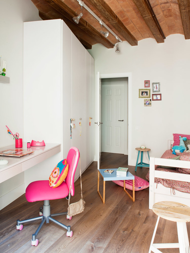 Ejemplo de habitación de niña de 1 a 3 años escandinava de tamaño medio con escritorio, paredes blancas y suelo de madera en tonos medios