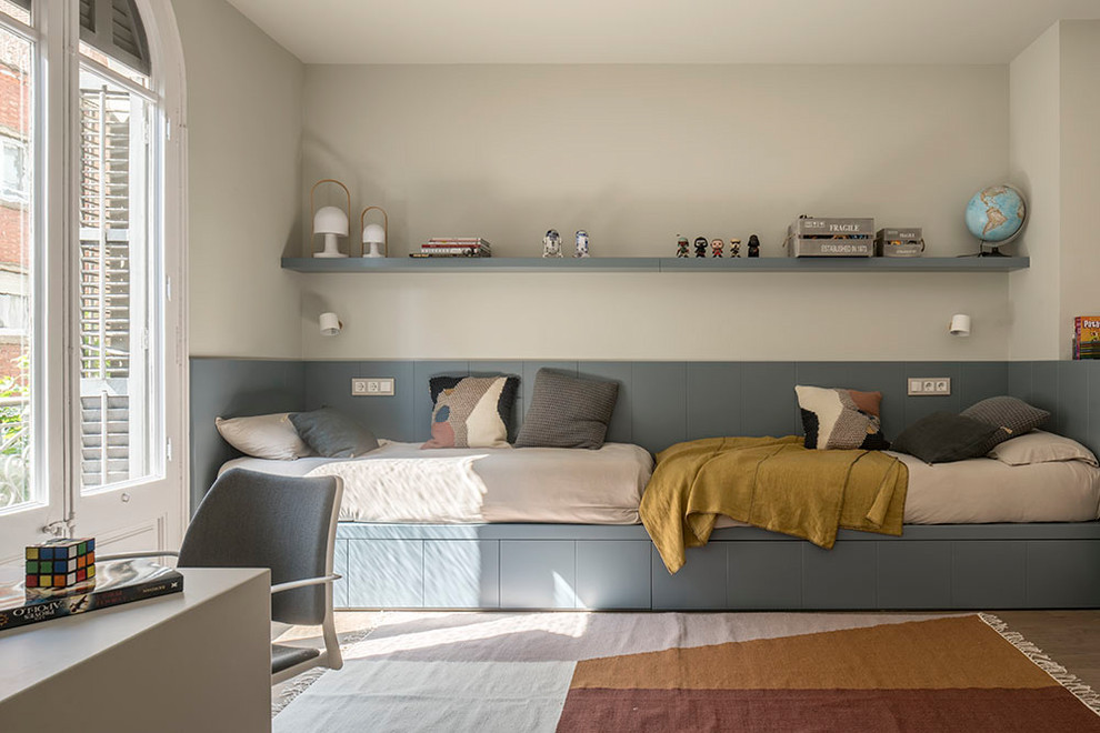 Large contemporary children’s room for boys in Barcelona with beige walls, medium hardwood flooring and brown floors.
