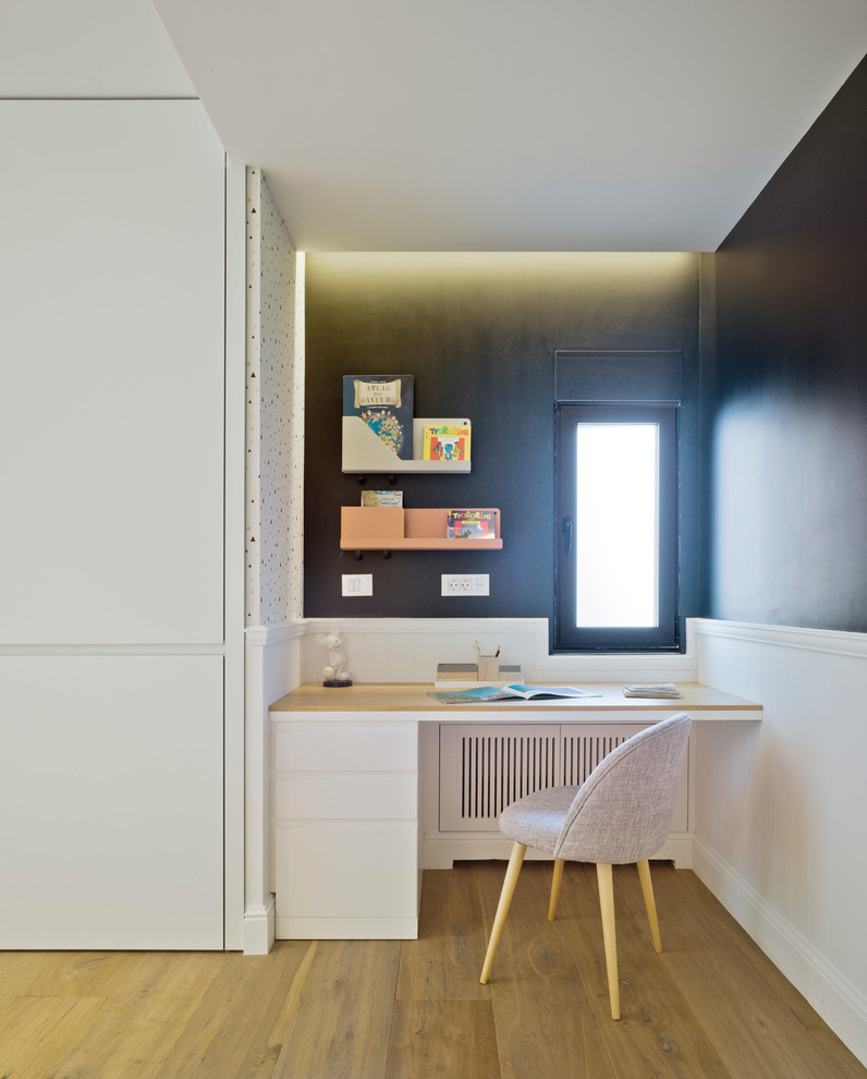 Diseño de habitación de niña actual de tamaño medio con escritorio, paredes negras, suelo de madera clara y suelo marrón