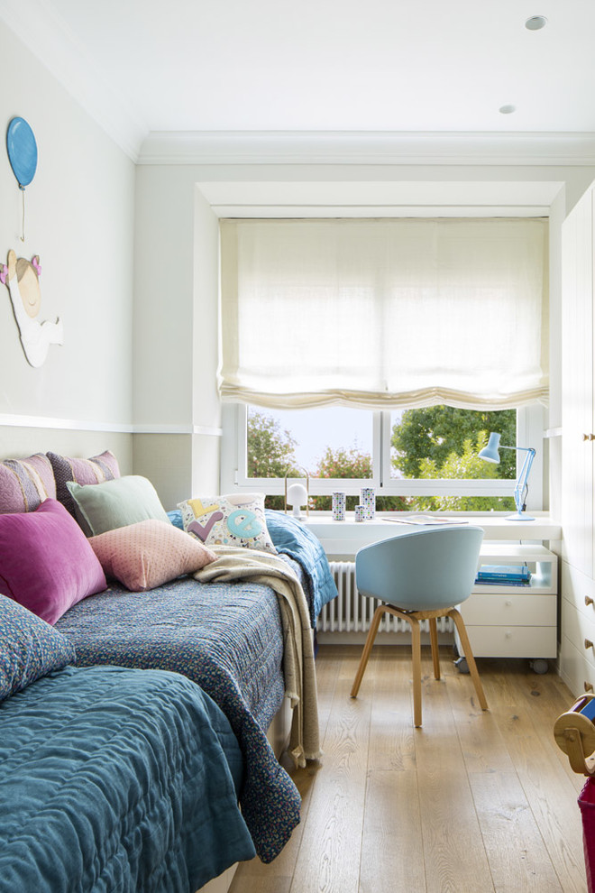 Foto på ett stort skandinaviskt könsneutralt barnrum kombinerat med sovrum och för 4-10-åringar, med vita väggar, mellanmörkt trägolv och brunt golv