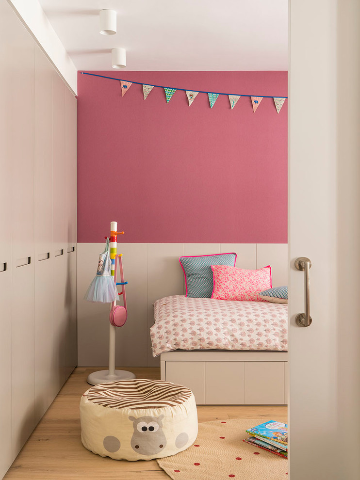 Esempio di una grande cameretta per bambini da 4 a 10 anni design con pareti rosa e pavimento in legno massello medio