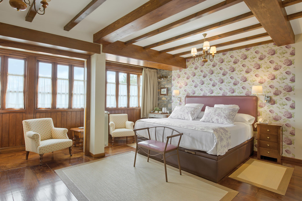 Modelo de dormitorio principal mediterráneo con paredes rosas, suelo de madera en tonos medios y suelo marrón