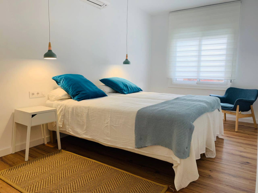 This is an example of a medium sized scandinavian guest bedroom in Other with white walls and laminate floors.